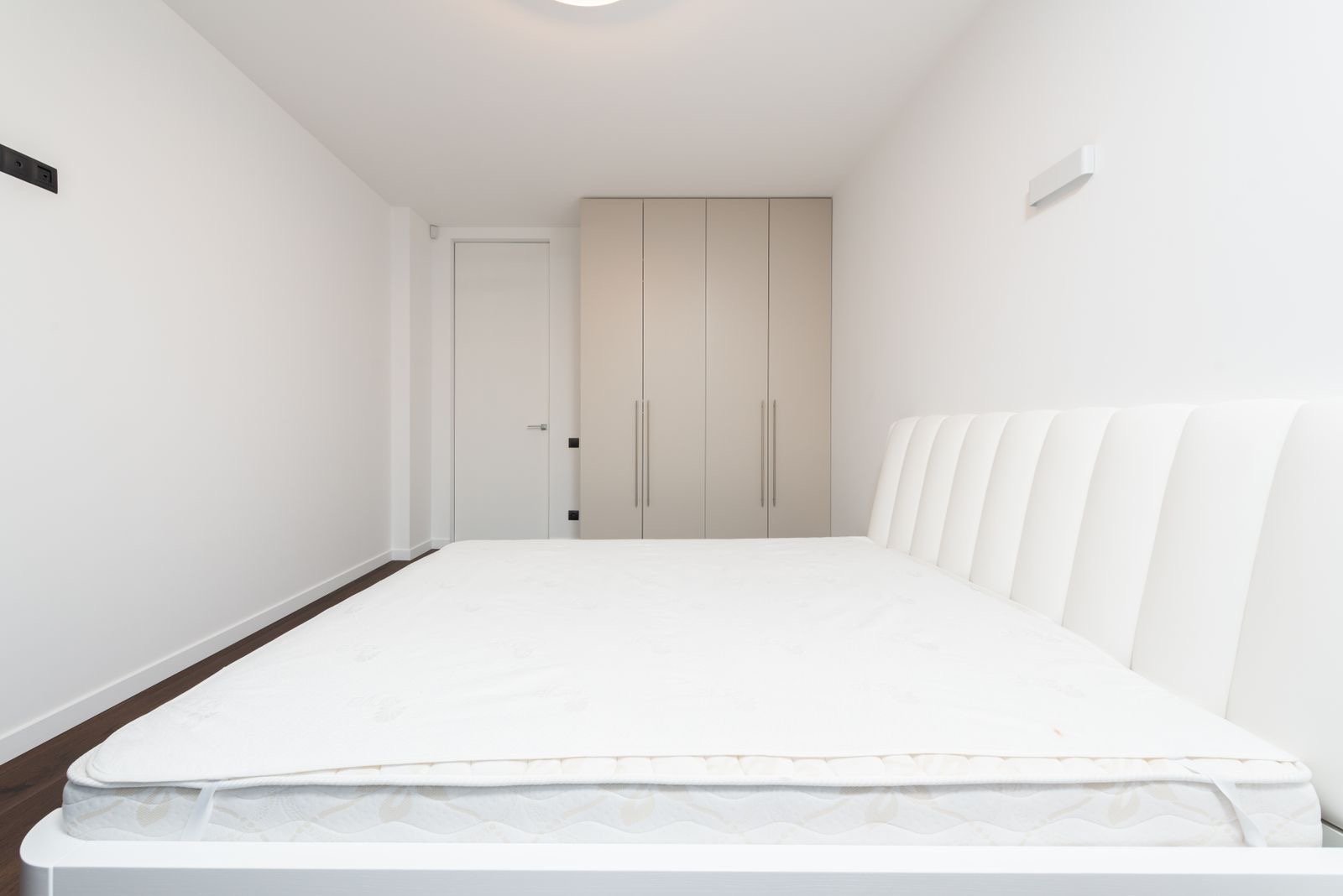 Wit matras met matrastopper op een bed in een lichte slaapkamer